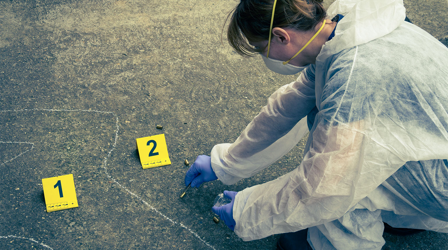 Am Tatort: Die Umrisse eines Menschen sind am Boden markiert. Eine Frau im Overall sichert Spuren.
