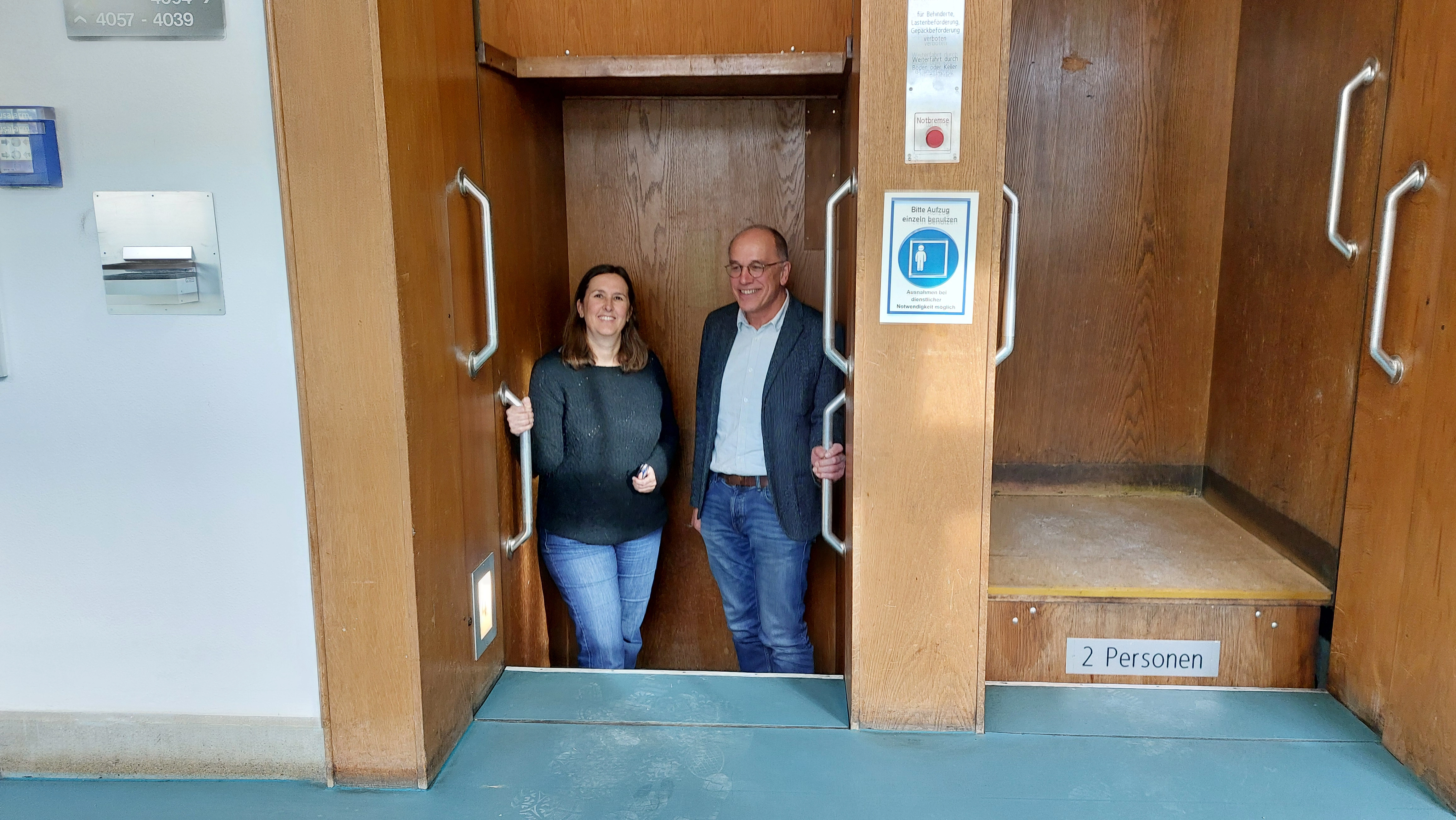 Andrea Kleim und Albert Krautenbacher fahren in einem Paternoster.  