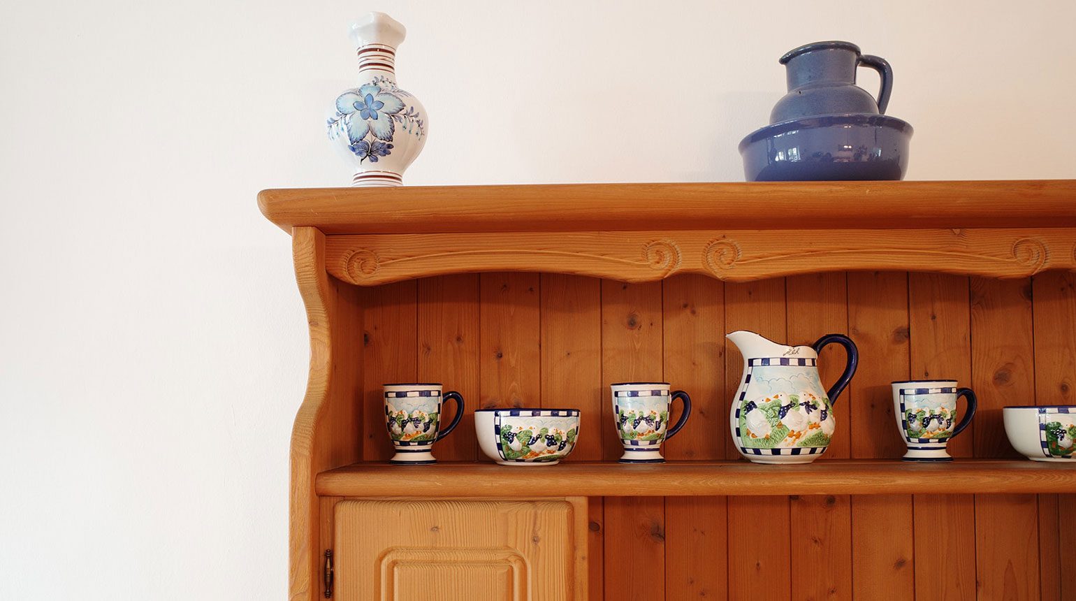 Detailaufnahme: Wohnzimmerschrank im bäuerlichen Stil mit bemaltem Keramikgeschirr. 