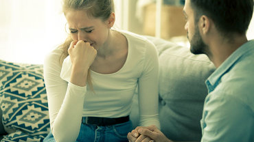 Ein Mann tröstet seine weinende Frau oder Partnerin.