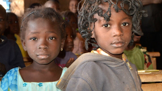 Porträtfoto: Zwei kleine Mädchen aus Burkina Faso blicken in die Kamera.