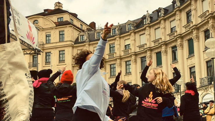 Flashmob auf dem Münchner Karlsplatz: Eine Gruppe von Frauen tanzt mit hochgereckten Armen.