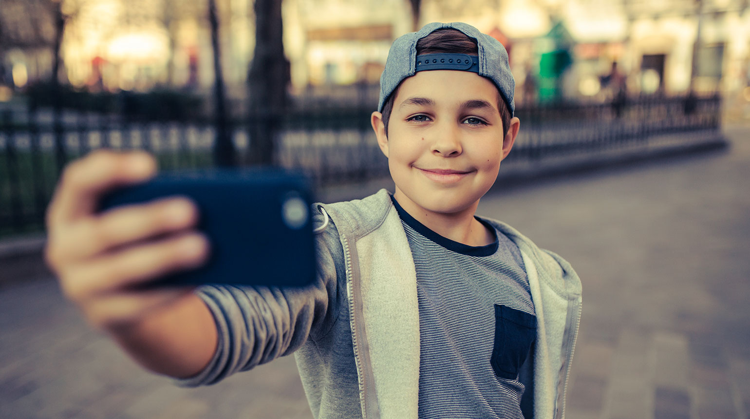Ein Junge macht mit seinem Smartphone ein Selfie.   