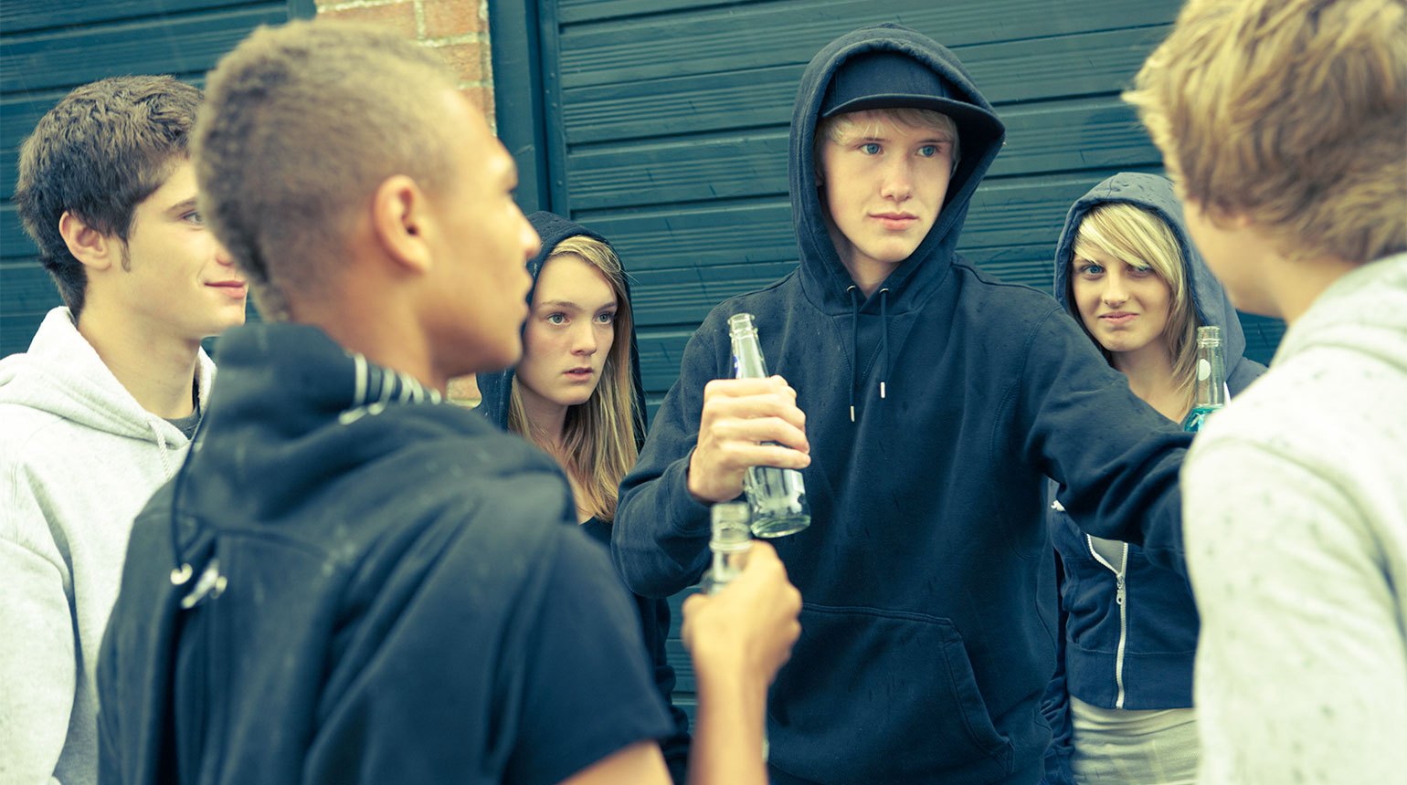 Ein Jugendlicher wird von einer Gruppe Gleichaltriger bedroht.