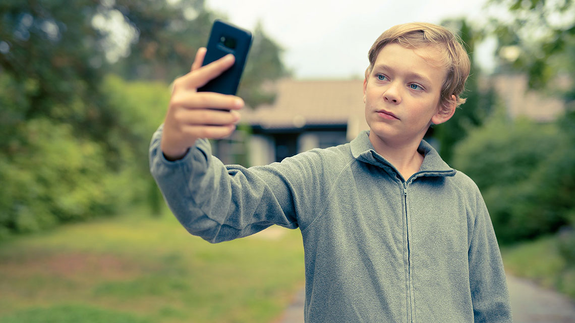 Ein Junge macht ein Selfie mit dem Smartphone.