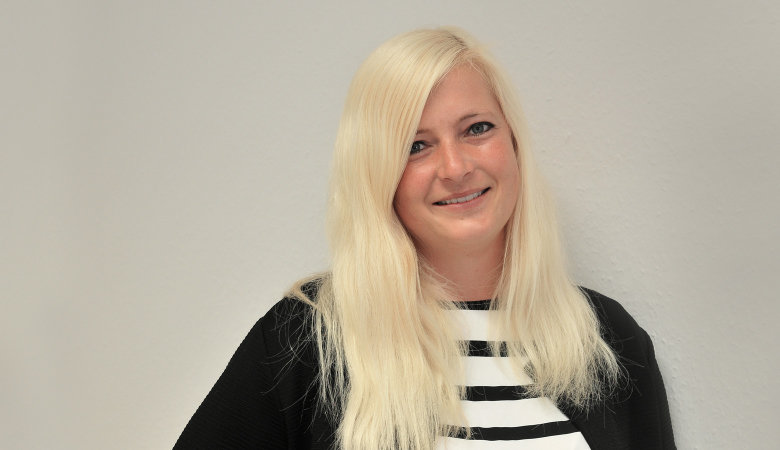 Porträtfoto: Carina Huber im Freien, vor einer Hauswand.